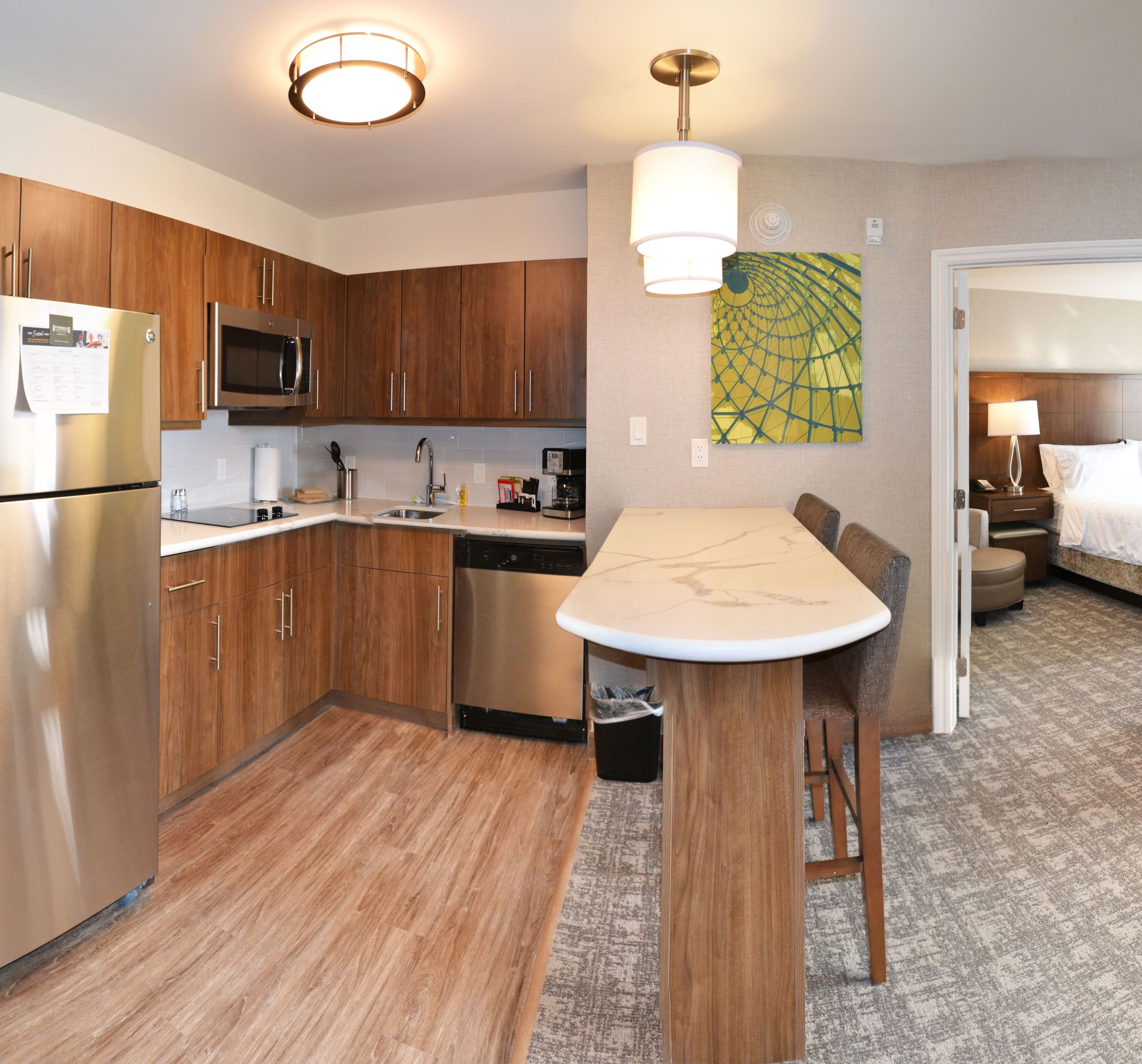 A modern kitchen with wooden cabinets, stainless steel appliances, and a dining area with a marble table.
