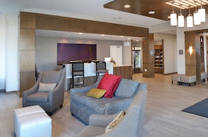 A lobby with seating, a reception desk, and a large wall mural. - King 1BR Suite w/ Kitchen, Hot Breakfast & Pool (Red Deer)