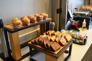 A bakery display with muffins and loaves of bread.