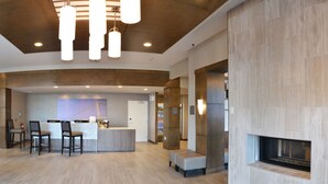 Un lobby moderno con mostrador de recepción, zona de estar y chimenea.