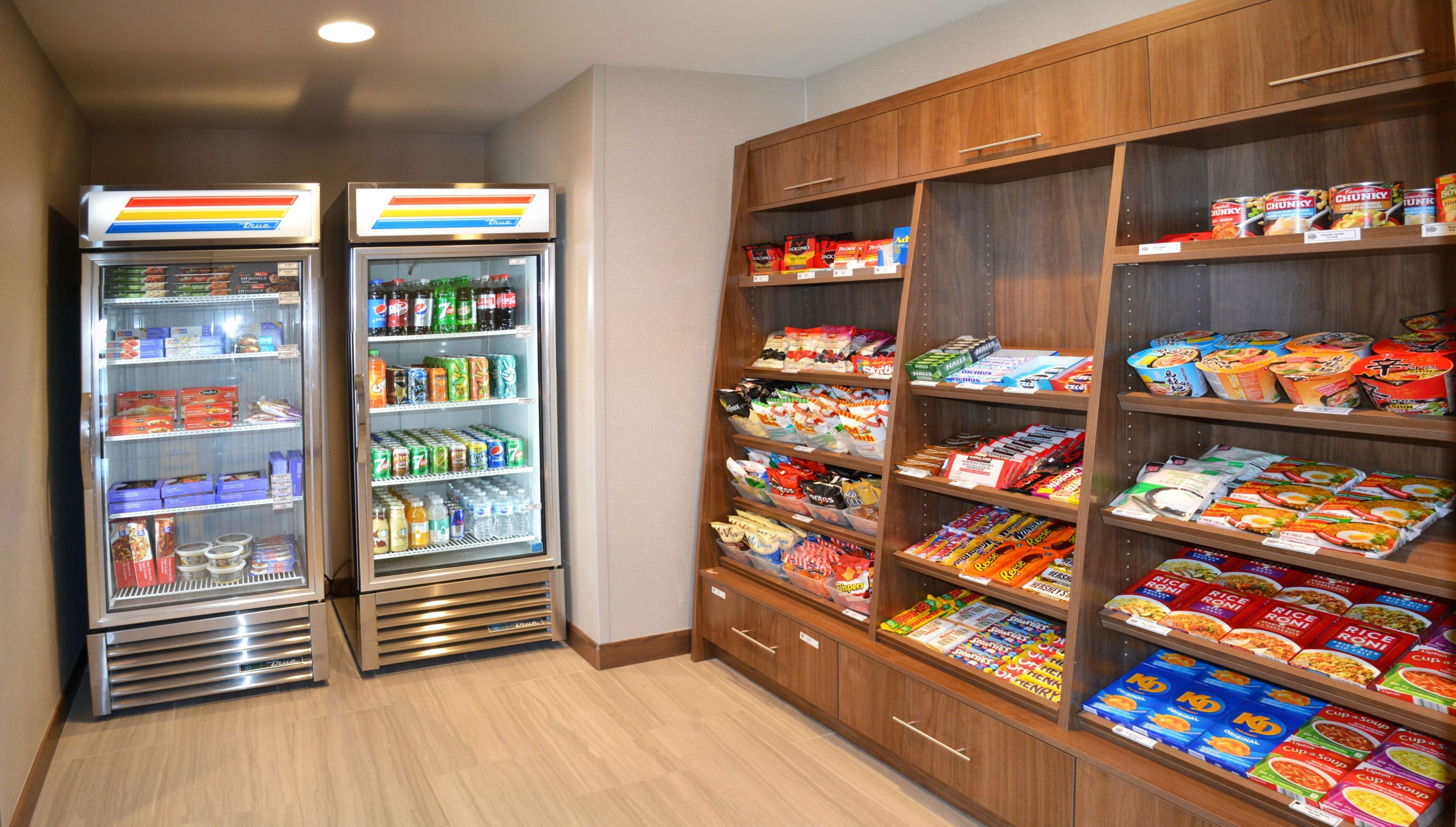 Zona de venta con opciones de bocadillos y bebidas, incluyendo un refrigerador y una estantería con diversos productos.