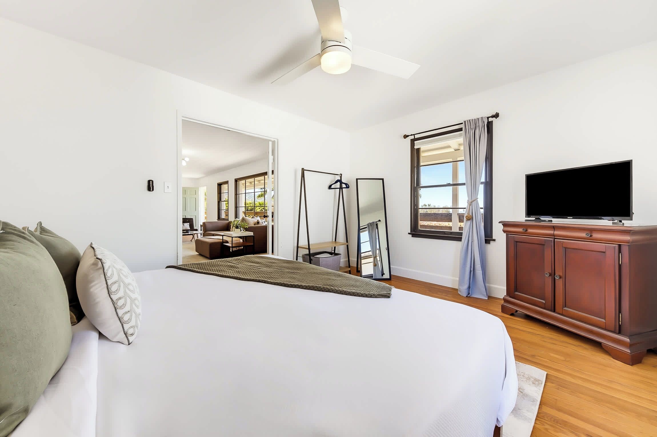 A hotel room with a bed, a television, a wardrobe, and a view of the outdoors.