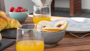 Een ontbijtsetting met gebak, een schaal fruit, een glas sinaasappelsap en een hangmat.