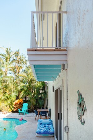 A residential building with a balcony, a pool, and outdoor furniture. - Heated Pool, Close to Downtown Delray, Six-Bedroom Estate! (Delray Beach)