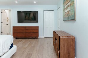 A bedroom with a bed, a dresser, a television, and a door. - Heated Pool, Close to Downtown Delray, Six-Bedroom Estate! (Delray Beach)