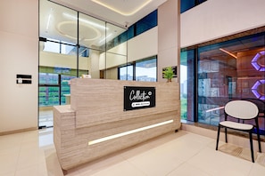 A reception desk with a sign indicating it is serviced by OYO. - Suite Room Hotel Nano Pod (Surat)