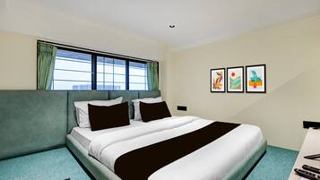 Una habitación de hotel con una cama, un ventanal con cortinas y tres cuadros enmarcados en la pared.