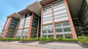A modern building with a flat roof, large windows, and a sign that reads 'Collector O 020-Service'. - Suite Room Hotel Nano Pod (Surat)