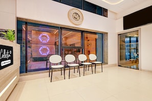 A modern interior with a reception area featuring a clock, seating, and a sign indicating OYO-Service. - Suite Room Hotel Nano Pod (Surat)