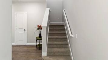 A staircase with carpeted steps and white walls, leading to an upper floor.