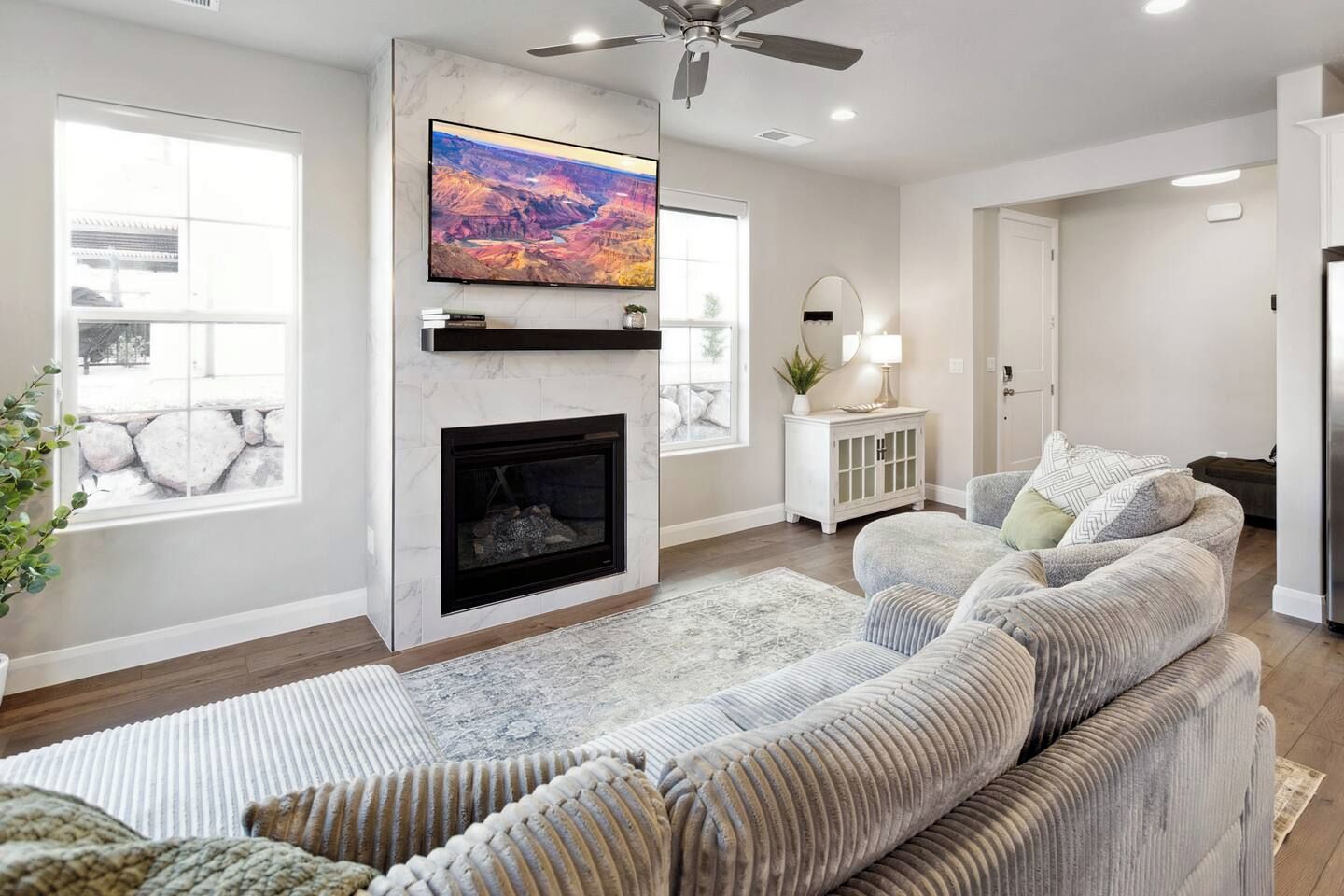 A living room with a fireplace, a large flat-screen TV mounted above it, a sofa, and a rug.
