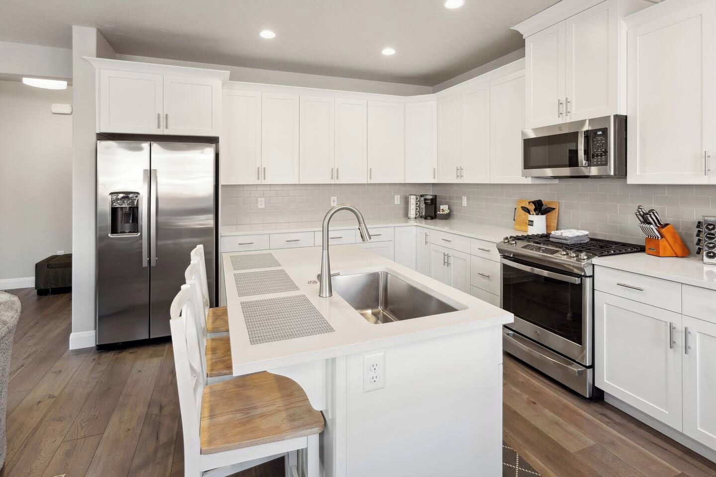 A modern kitchen with white cabinetry, stainless steel appliances, and a central island with a sink.