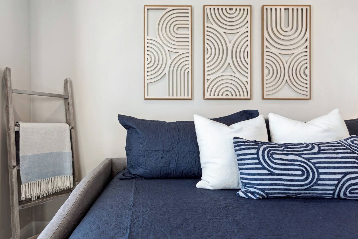 A bed with dark blue bedding, two pillows, and a decorative wall panel.