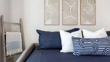 A bed with dark blue bedding, two pillows, and a decorative wall panel.