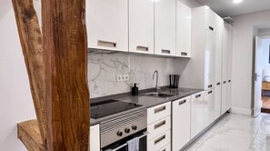 A modern kitchen with white cabinets, a black countertop, and a stainless steel sink. - VIVA Janelas Verdes Residence (Lisboa)