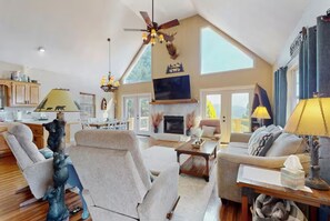 Vaulted living room with a fireplace, mounted television, and plush seating. - Lake & Mountain Views | Hot Tub | 3 King Suites (Hayesville)