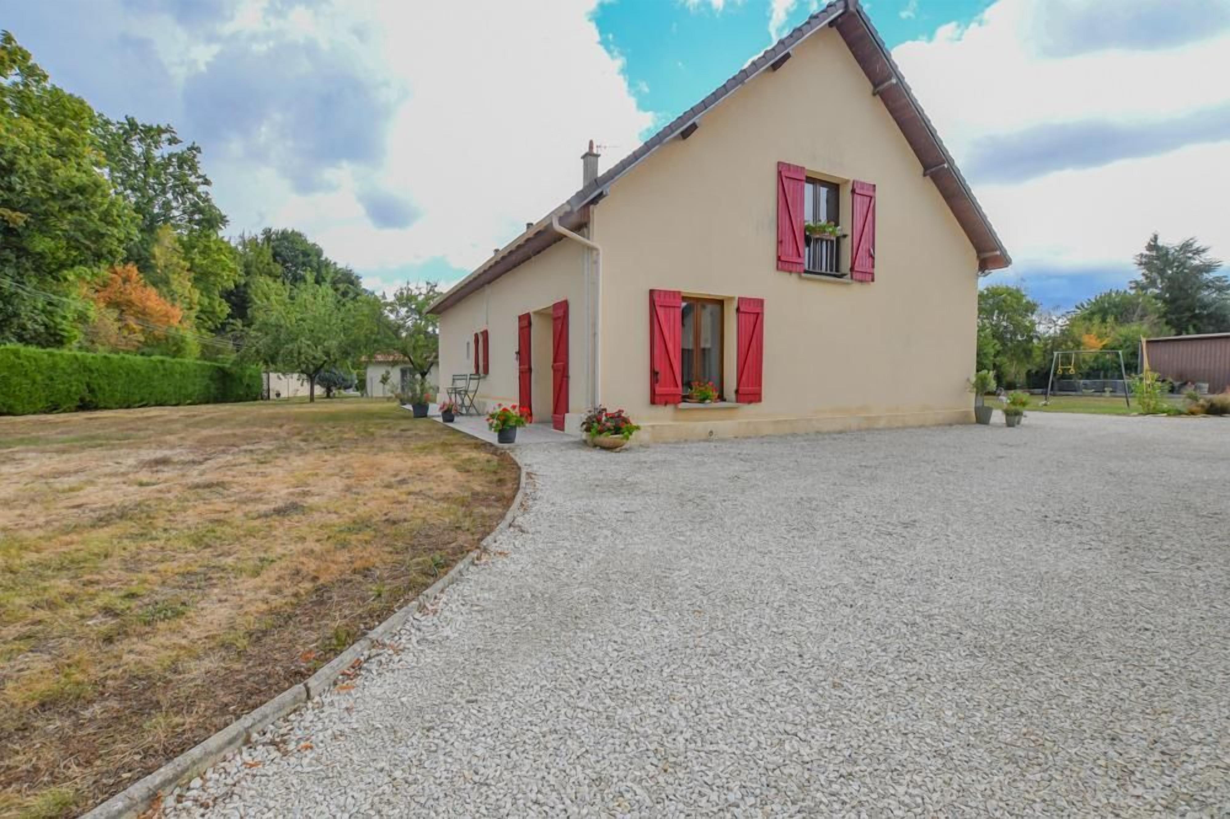 A two-story house with a gravel driveway and a well-maintained lawn.