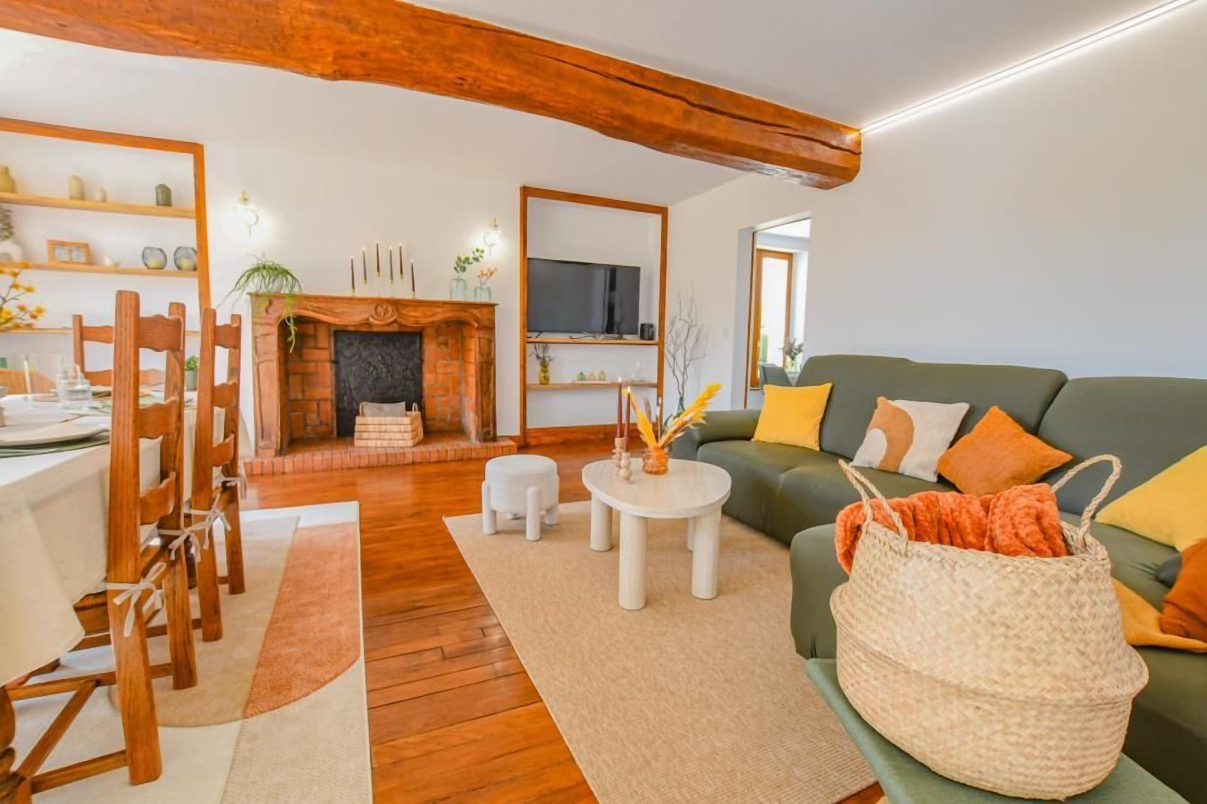 Un salon avec une cheminée, un canapé, une table basse et un coin repas avec des chaises.