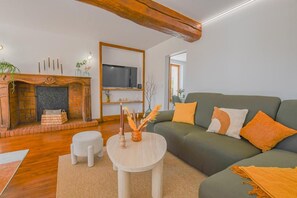 Ein Wohnzimmer mit Kamin, einer Couch, einem Fernseher und einem Couchtisch.