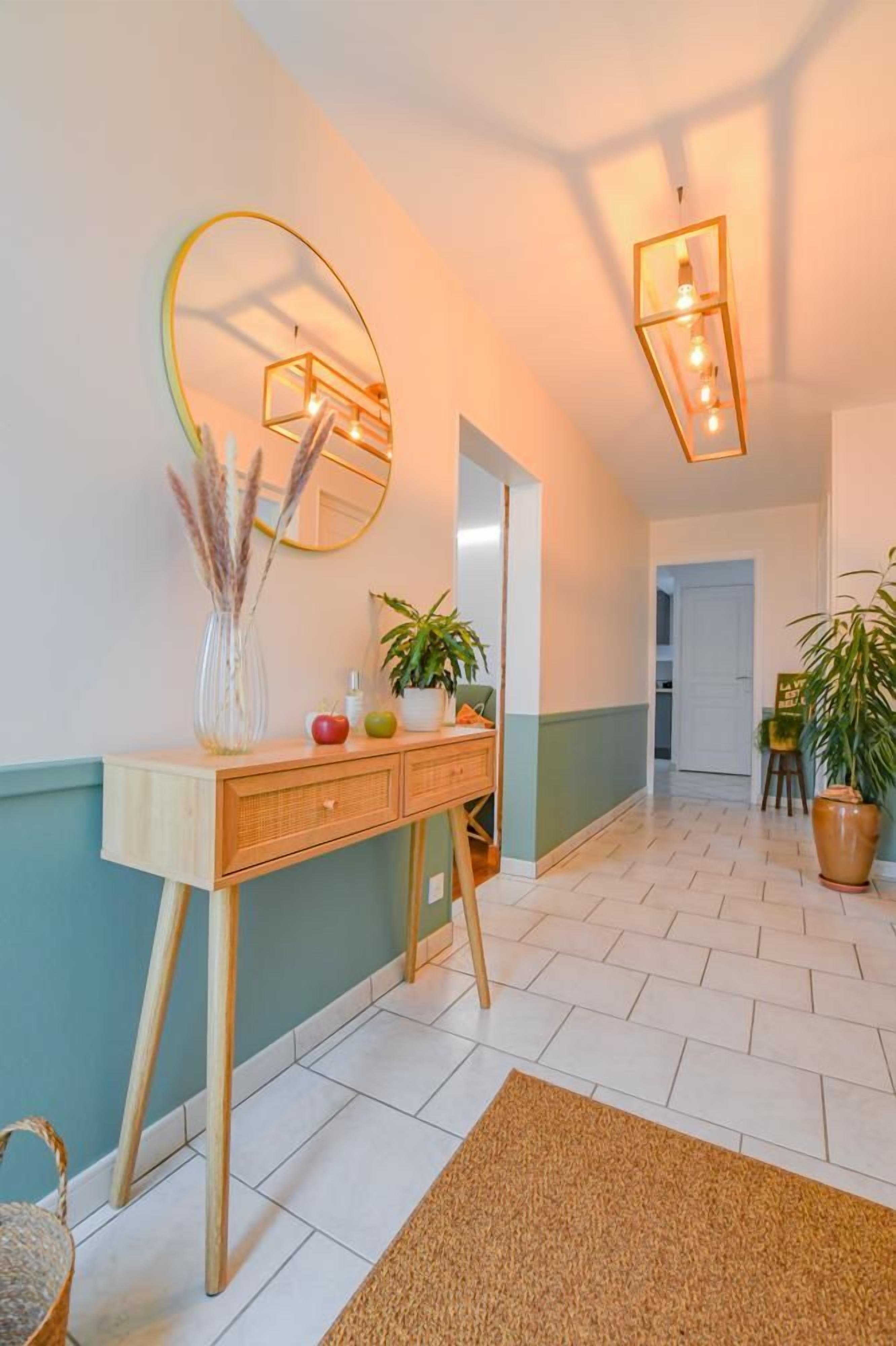 A hallway with a wooden console table, a mirror, and a potted plant.
