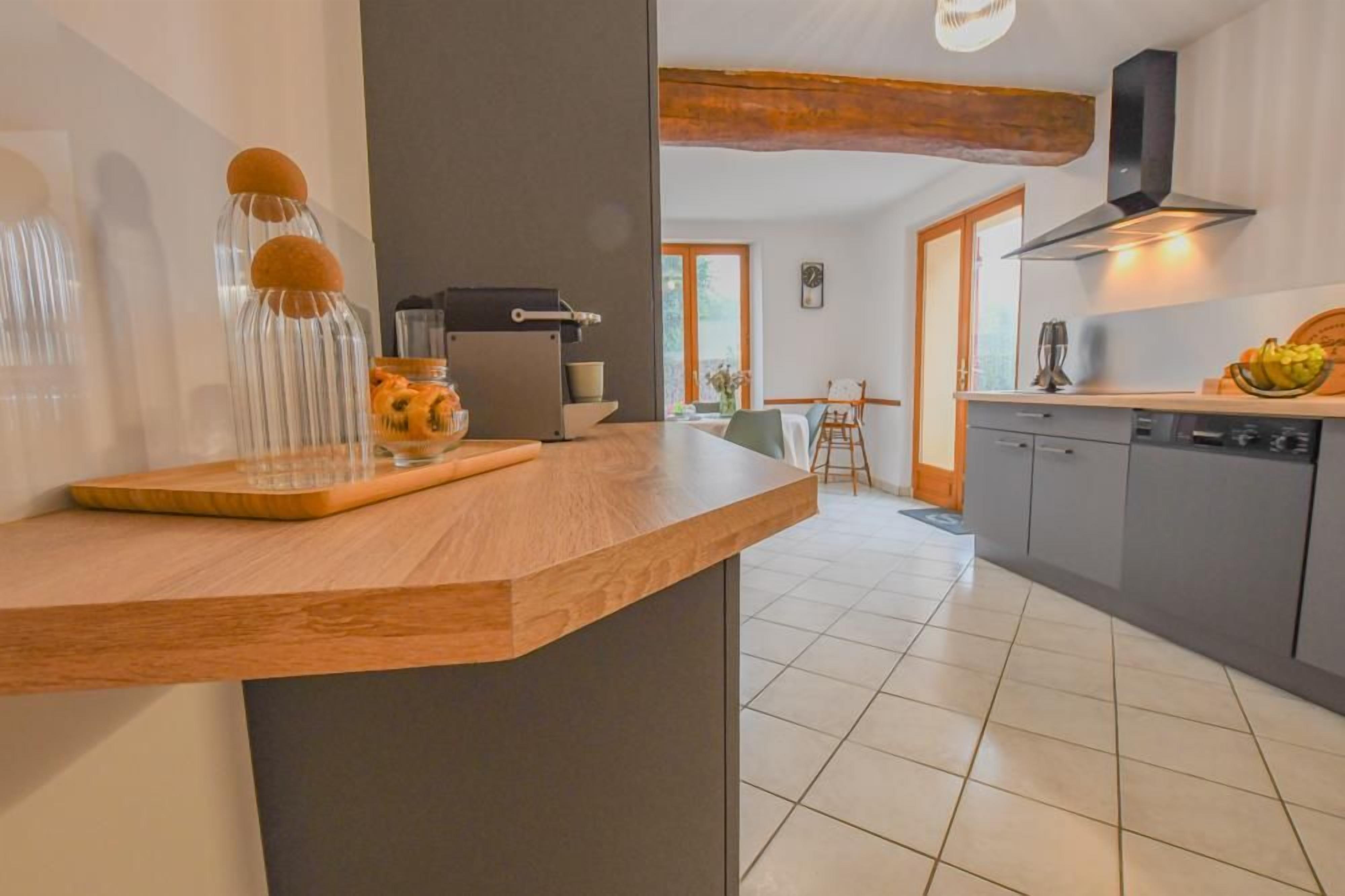 A modern kitchen with a wooden countertop, a built-in stove, and a dining area with a table and chairs.