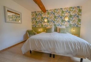 Ein Schlafzimmer mit einem Bett, einem Kopfteil, einer Wand mit einem tropischen Blattmuster und einem gerahmten Bild.