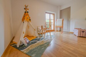 Ein Zimmer mit einem Zelt, einem Malständer, einem Stuhl und einer Kommode.