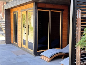 A modern outdoor seating area with a wooden bench and a cushioned lounge chair.