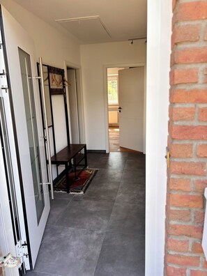 A hallway with a bench, a rug, and a brick wall.