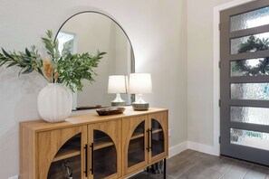 A wooden console with a mirror, two lamps, and a vase with plants. - Easton Park 4BR with Private Resort-Style Pool (Austin)