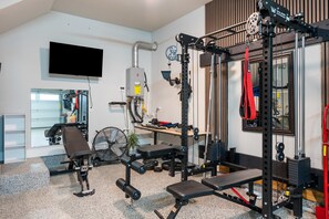 A home gym with a pull-up bar, weight bench, and various exercise equipment. - Easton Park 4BR with Private Resort-Style Pool (Austin)