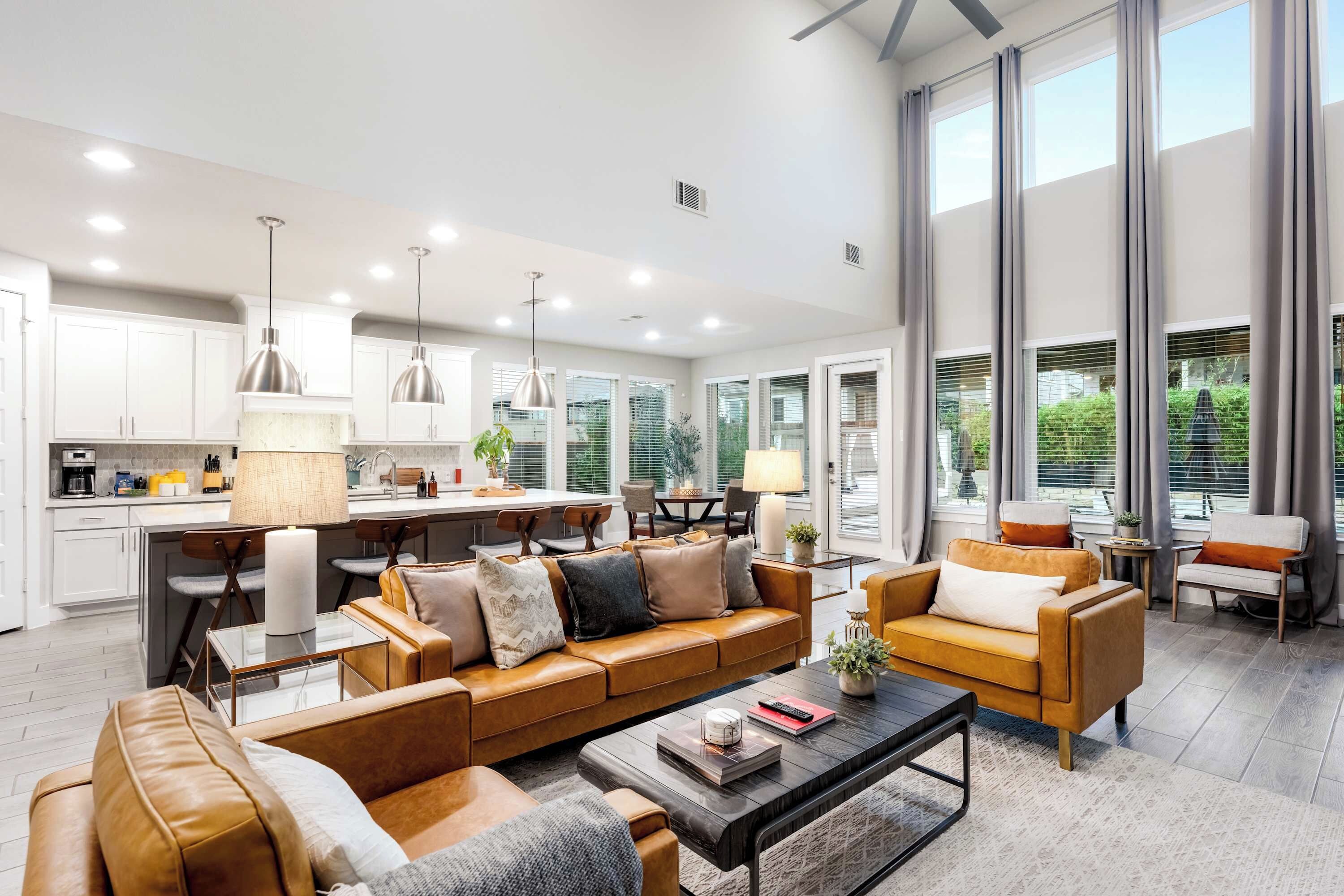 A modern living room with a brown leather sofa, a coffee table, and a dining area with a kitchen in the background.