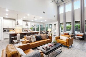 Ein modernes Wohnzimmer mit einem braunen Ledersofa, einem Couchtisch und einem Essbereich mit einer Küche im Hintergrund.