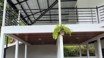A covered outdoor area with a metal roof, white walls, and a wooden deck.