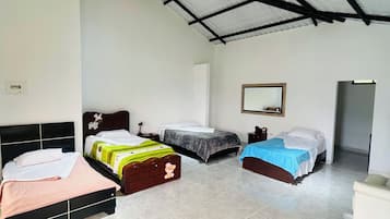 Ein Zimmer mit drei Betten, einer weißen Wand, einer Decke mit schwarzem Metallfachwerk und einem gefliesten Boden.