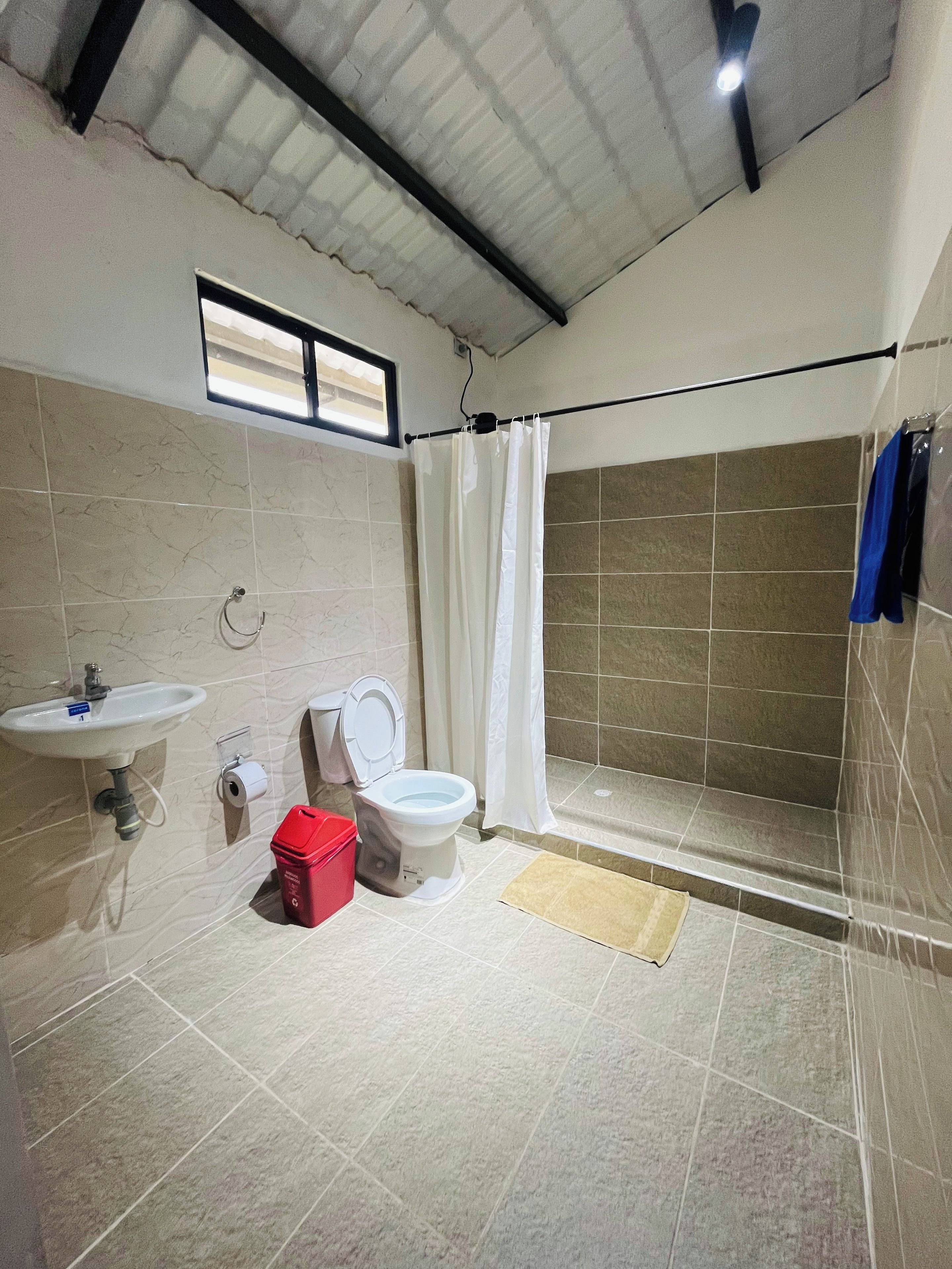 Ein Badezimmer mit Toilette, Waschbecken, Dusche und einem Fenster.