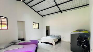 A room with two beds, a ceiling fan, and a window.