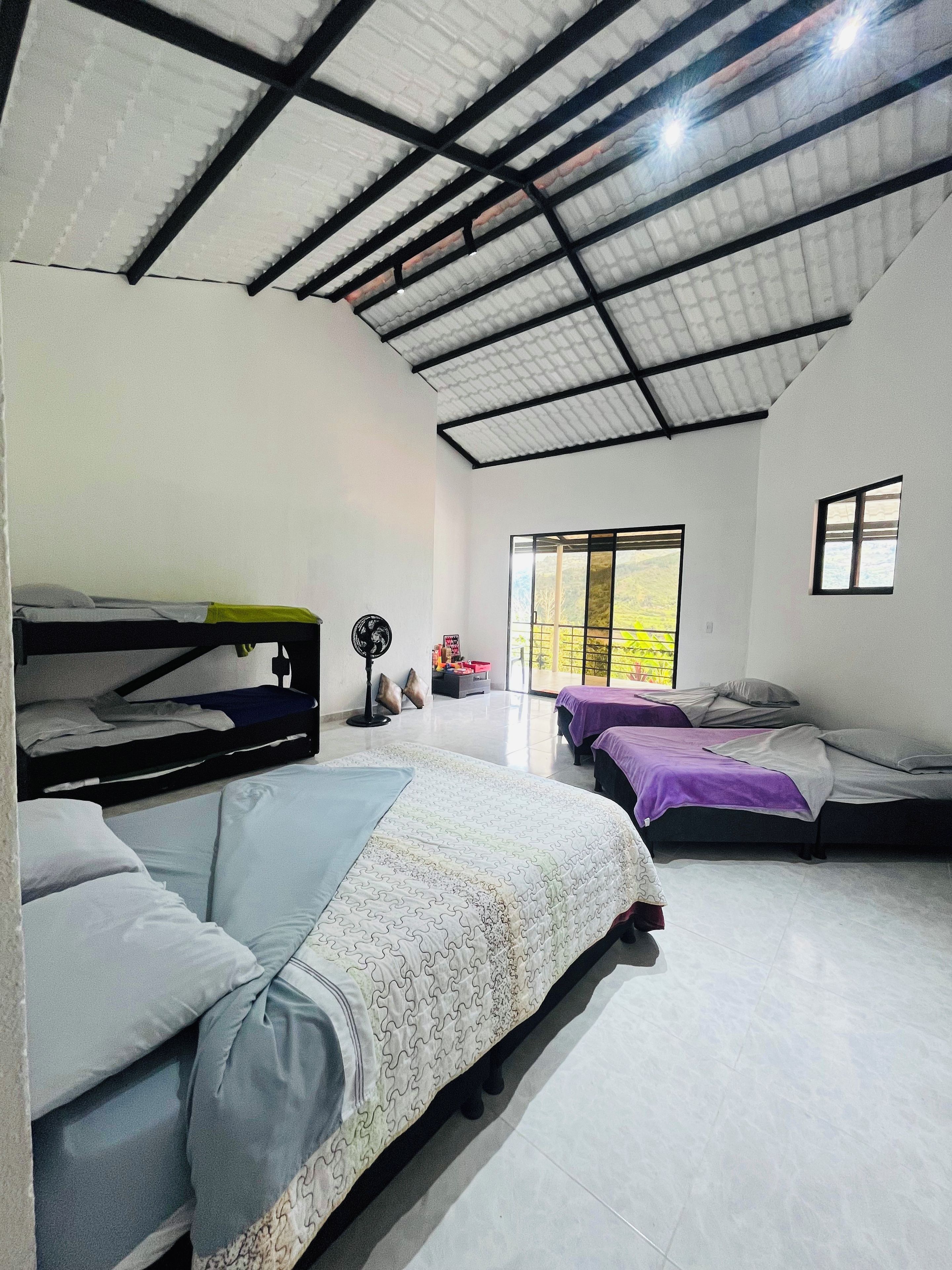 Une chambre avec des lits superposés, un ventilateur et une fenêtre donnant sur un beau paysage.