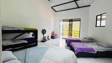 Une chambre avec des lits superposés, un ventilateur et une fenêtre donnant sur un beau paysage.