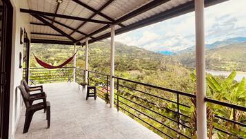 A covered terrace with a view of a mountainous landscape.