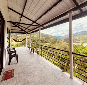 A covered terrace with a view of a mountainous landscape.
