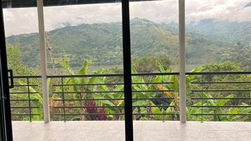 A room with a large sliding glass door leading to a balcony with a view of a mountainous landscape.