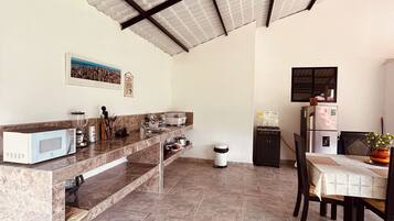 A kitchen with a marble countertop, a microwave, a sink, and a dining area with a table and chairs.