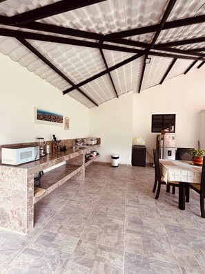Cuina amb taulell de marbre, microones, rentapelats i zona de menjador amb taula i cadires.