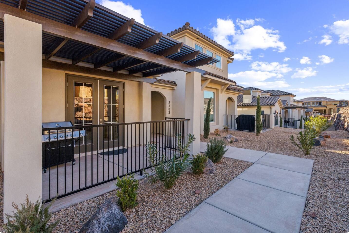 A residential building with a covered patio, outdoor grill, and a well-maintained garden.