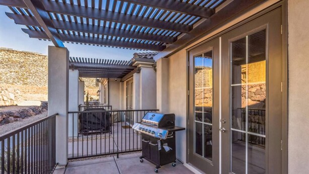 A covered patio with a grill, a door leading to a stone wall, and a view of the surrounding landscape. - Heated Pool & Pickleball - Beautiful 3BR Home Near Zion (Washington)