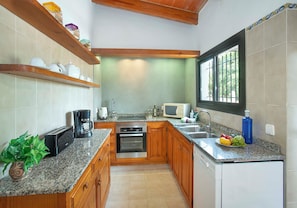 A kitchen with wooden cabinets, a microwave, a coffee maker, and a sink. - Countryside Retreat in La Font, A/C, Private Pool, Large Garden - 15mins Walk to Old Town Pollenca! (Pollença)