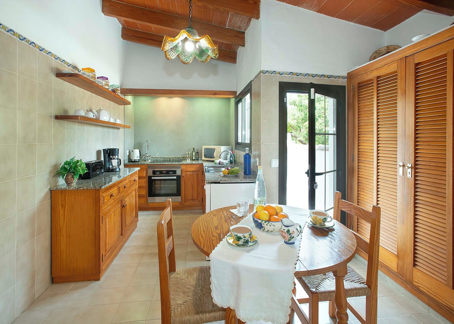 A kitchen with wooden cabinets, a dining table with chairs, a coffee maker, and a microwave.