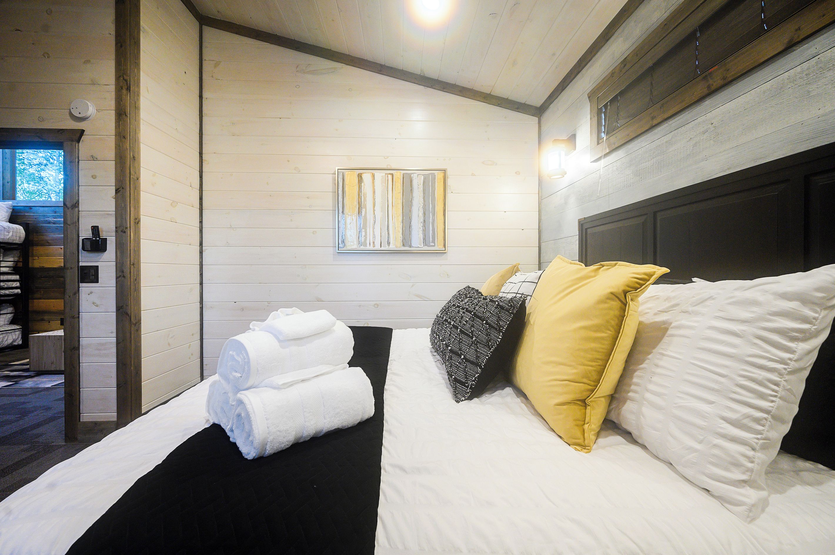 A hotel room with a bed, towels, a painting, and a window.