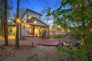 A cabin with a hammock, a fire pit, and a view of a train in the background. - Champagne Bliss | 2 King Suites + Hot Tub (Broken Bow)